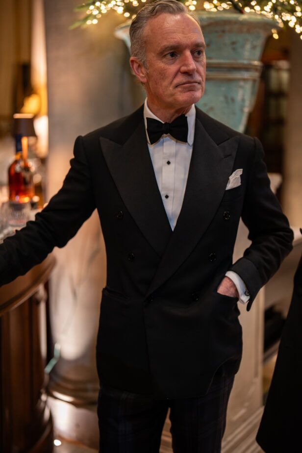 Black double-breasted peak lapel tuxedo with bow tie, worn by a guest at the bar