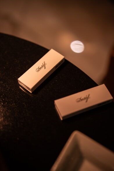 Two cream Davidoff cigar boxes on a dark marble table beside an ashtray