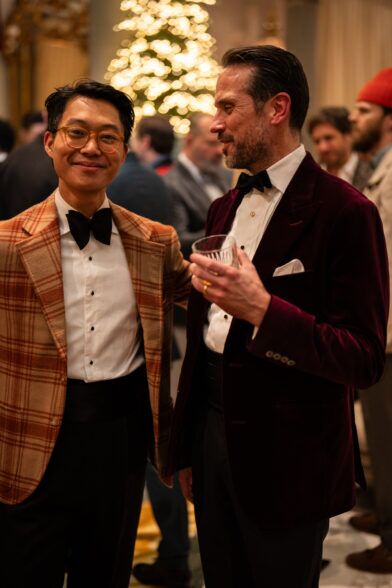 Rust plaid dinner jacket and a burgundy velvet jacket, worn by two guests with drinks