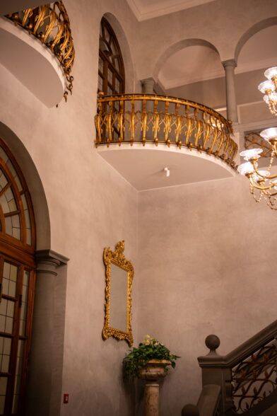 Gilded balcony railings and a carved mirror in the St Regis Florence stairwell