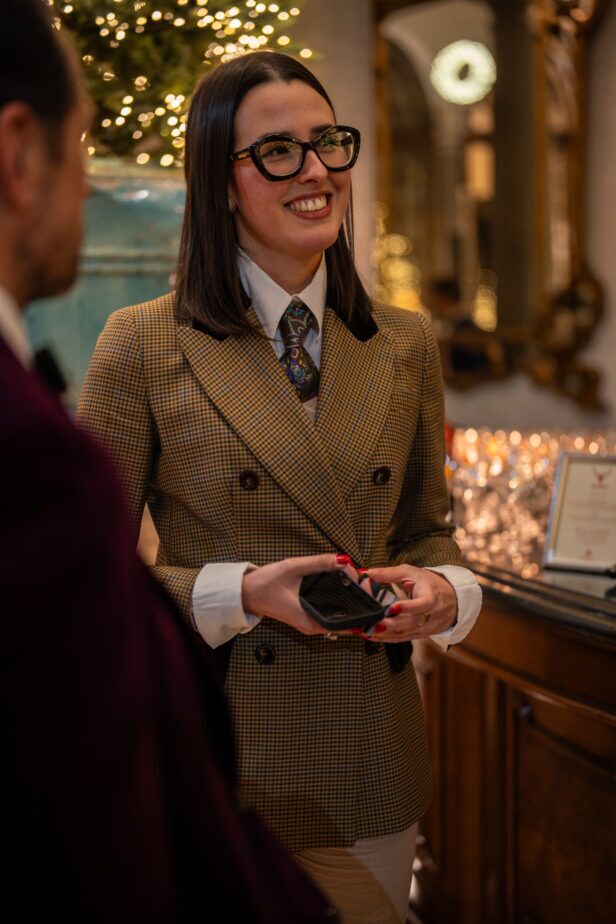 Tan houndstooth double-breasted jacket with velvet collar and paisley tie, worn by a guest
