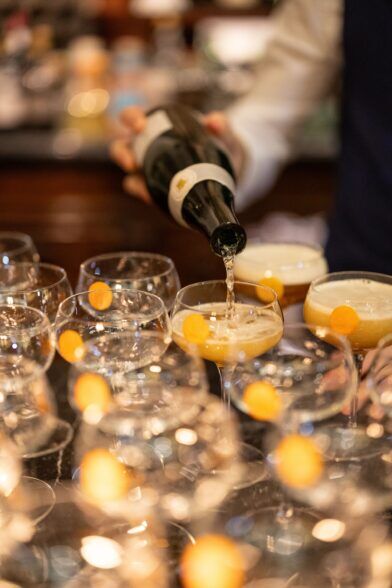 Champagne poured into coupe glasses lined up on a marble bar