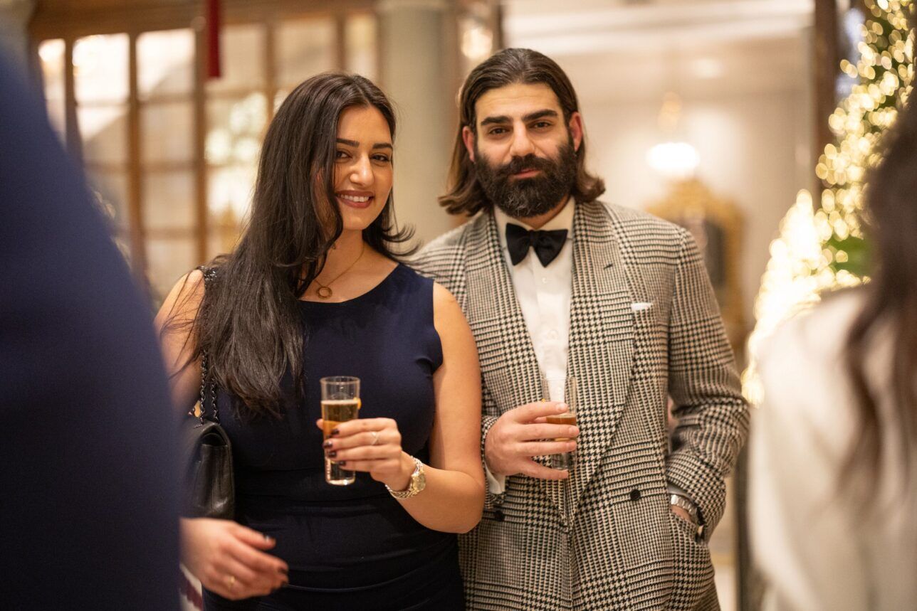 Grey glen check double-breasted jacket with a black bow tie, worn by a party guest