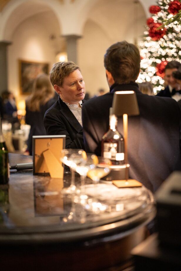 Black velvet jacket with a white shirt, worn by a guest at a lamplit hotel bar