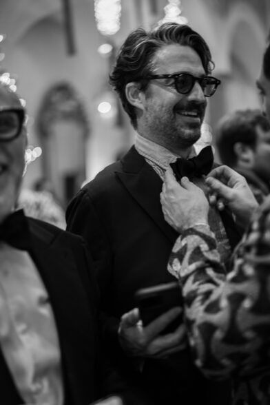 Black dinner jacket with a bow tie being adjusted, in a black and white photograph