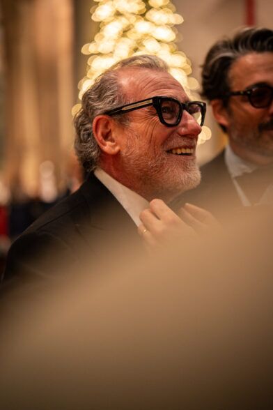 Black dinner jacket with a white shirt, worn by a smiling guest in heavy glasses