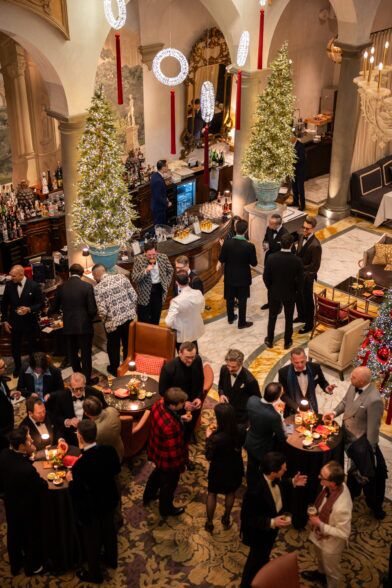Hotel bar and lobby filled with black tie guests beneath lit Christmas trees