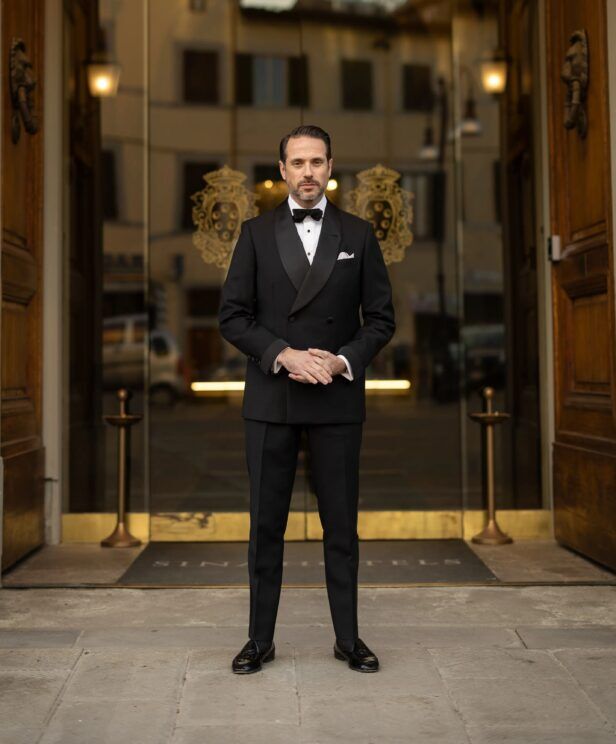 Black double-breasted shawl collar tuxedo with bow tie, worn by a model in a doorway