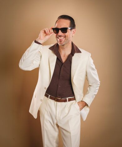 Ivory suit with brown open-collar knit shirt and brown croc belt, worn by a model