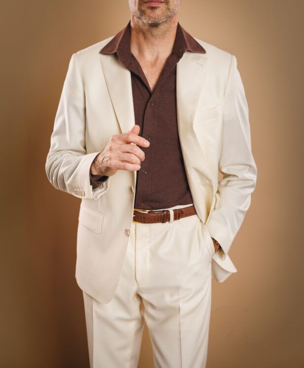 Ivory suit with brown pique knit polo shirt and brown croc-embossed belt, worn by a model