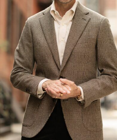 Brown glen check wool sport coat with cream shirt and dark corduroy trousers, worn by a model on a city street