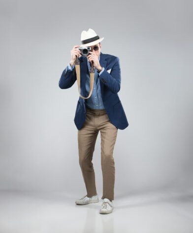 Navy hopsack sport coat with chambray shirt, tan trousers, panama hat and white sneakers, worn by a model