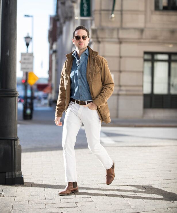 Tan suede field jacket with chambray shirt, white jeans and brown Chelsea boots, worn by a model on a city street