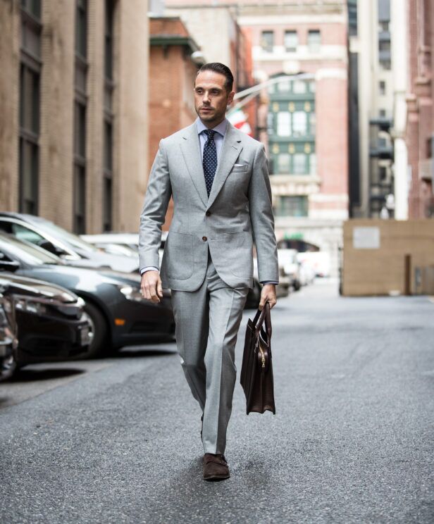 Light grey flannel suit with blue shirt, navy polka dot tie and brown suede double monks, worn on a city street