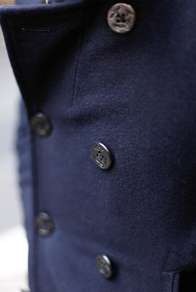 Navy wool peacoat with double-breasted front and dark anchor buttons, a close-up detail