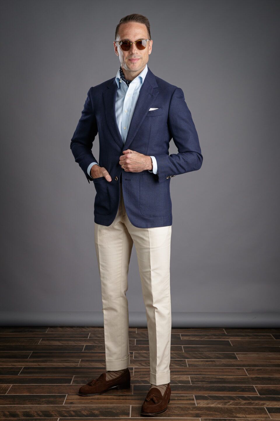 Navy hopsack sport coat with light blue shirt, navy dot neckerchief, stone chinos and brown suede tassel loafers, worn by a model