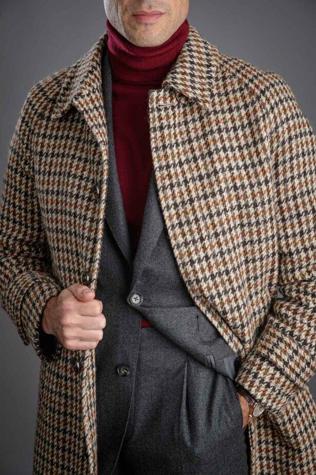 Brown and cream houndstooth wool balmacaan coat over grey flannel suit and burgundy turtleneck, worn by a model