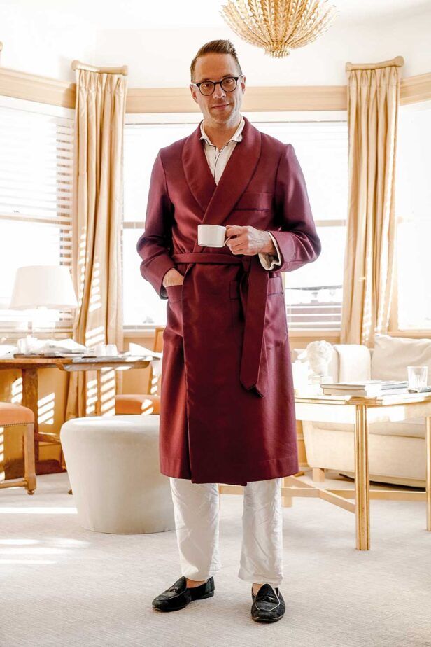 Burgundy shawl collar dressing gown with belt, worn with white pyjamas and velvet slippers by a model