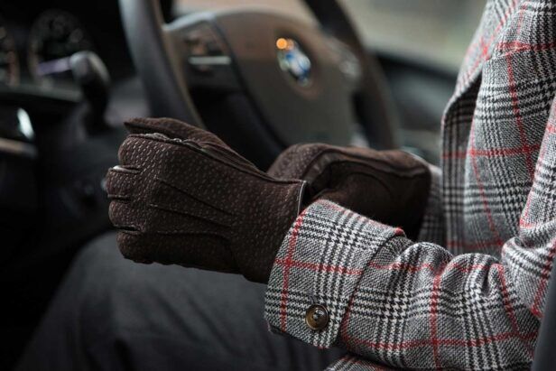Brown carpincho leather gloves with grey and red glen check sport coat, worn by a model in a car