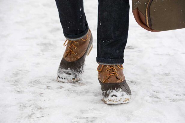 Brown leather and rubber duck boots with cuffed dark denim jeans, worn in the snow