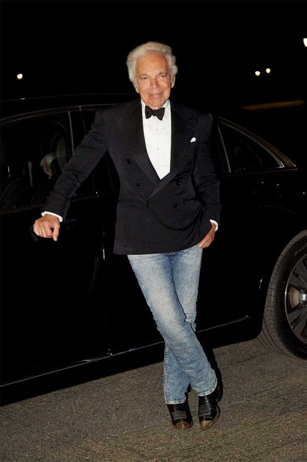 Black double-breasted tuxedo jacket with white dress shirt, black bow tie, faded jeans and cowboy boots, styled at night