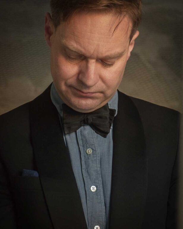 Black shawl collar dinner jacket with velvet butterfly bow tie and blue chambray shirt