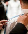 White dress shirt being measured across the shoulders with a blue tape measure, a back view fitting scene