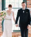 Black double-breasted peak lapel tuxedo with black bow tie and white pocket square, worn by a groom in a styled wedding scene