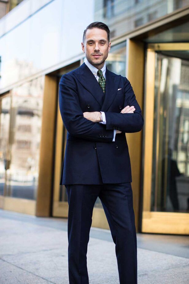 Navy double-breasted flannel suit with white shirt and green medallion tie, worn by a model on a city street