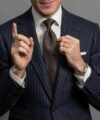 Navy chalk stripe flannel suit jacket with white shirt and brown geometric silk tie, worn by a model