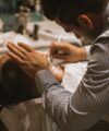 Blue and red checked dress shirt with rolled sleeves, worn by a barber giving a straight razor shave