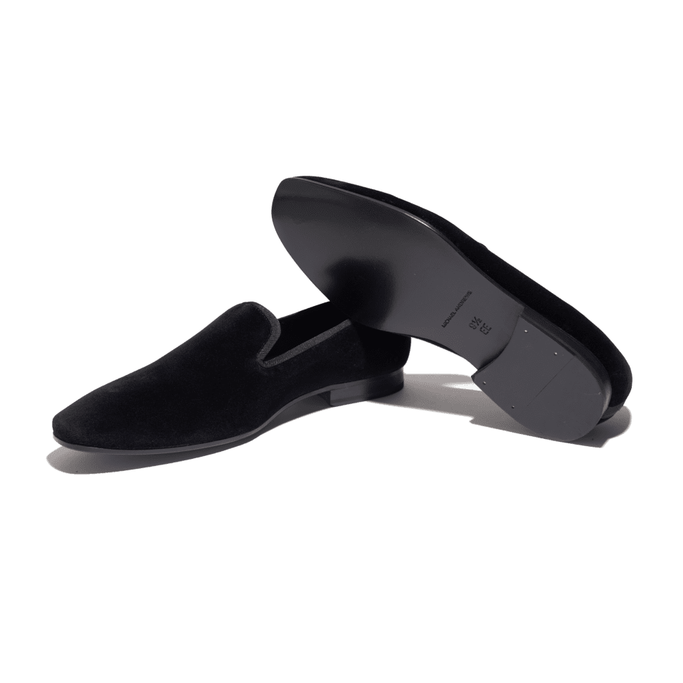 Black velvet formal slippers with grosgrain trim and leather soles, pair shown with one sole up, flat lay