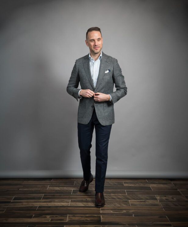 Grey puppytooth wool sport coat with blue striped shirt, navy trousers and brown loafers, worn by a model