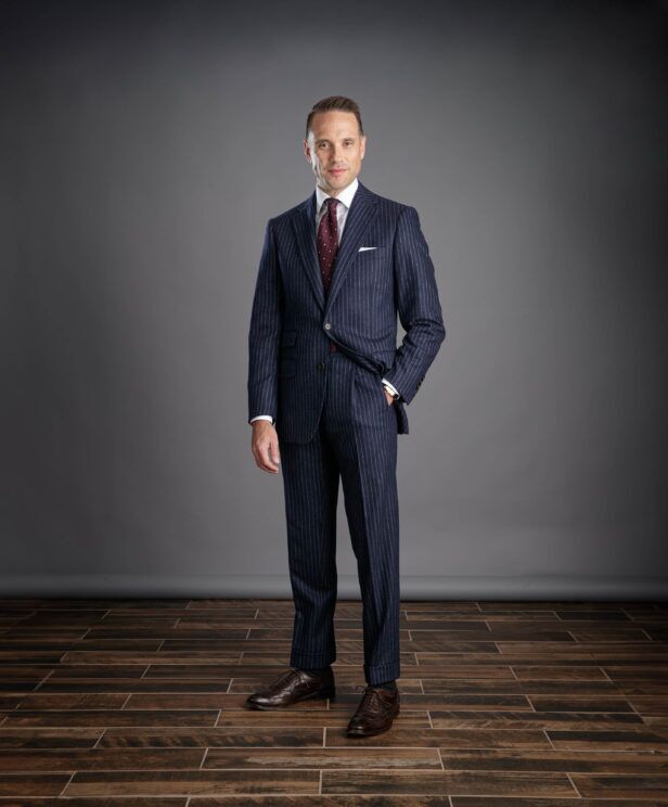 Navy chalk stripe flannel suit with white shirt, burgundy dotted tie and brown brogues, worn by a model