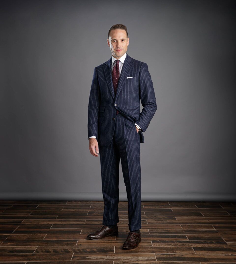 Navy chalk stripe flannel suit with white shirt, burgundy dotted tie and brown brogues, worn by a model