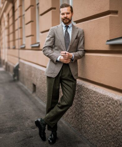 Brown houndstooth tweed sport coat with striped shirt, medallion tie and olive flannel trousers, worn by a model on a street