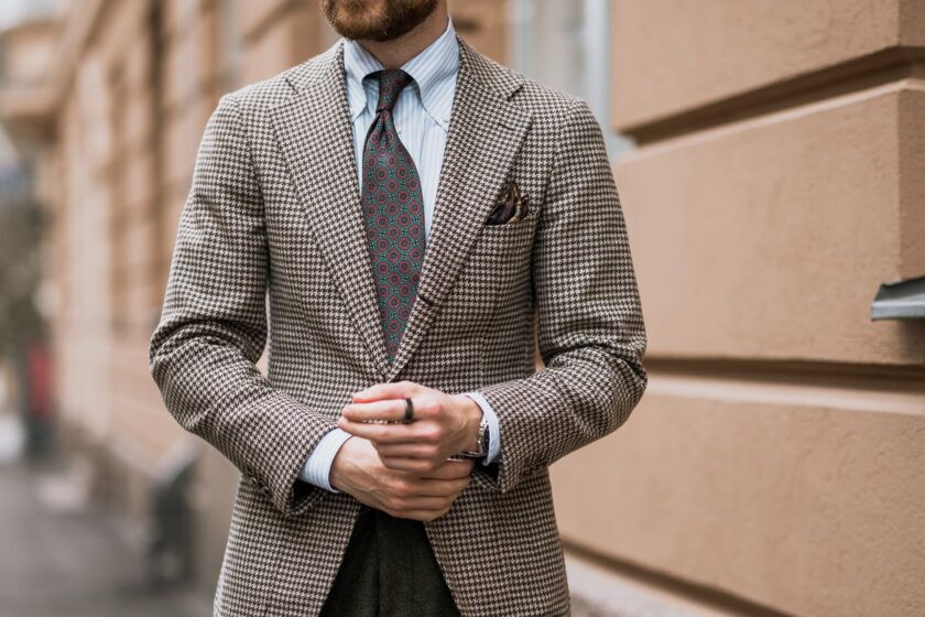 Brown and cream houndstooth tweed sport coat with blue striped shirt and green medallion tie, worn by a model