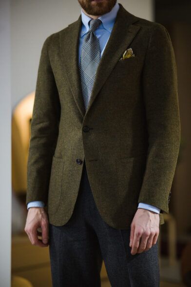 Olive green wool sport coat with blue shirt, grey glen check tie and charcoal flannel trousers, worn by a model