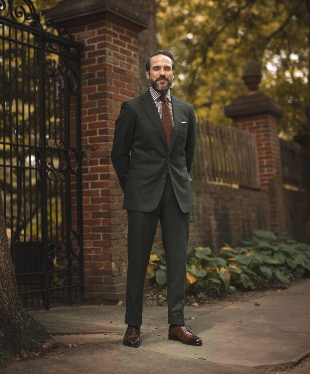 Forest green flannel suit with brown check shirt, brown tie and brown derby shoes, worn by a model outdoors