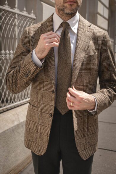 Brown glen plaid wool sport coat with white shirt, brown wool tie and dark green trousers, worn by a model
