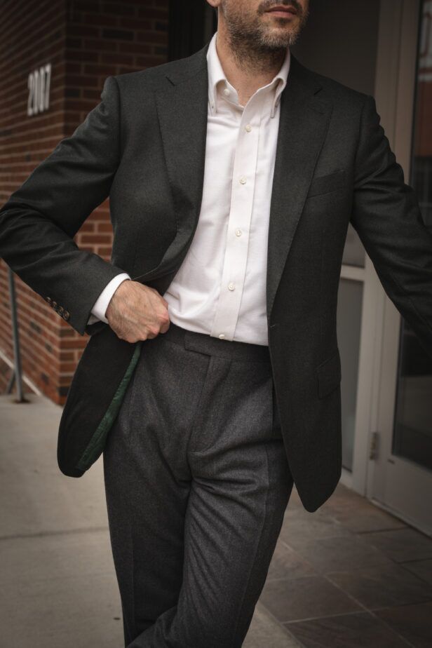 Dark olive wool sport coat with cream brushed cotton button-down shirt and grey flannel trousers, worn by a model