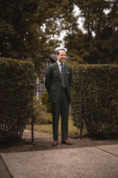 Forest green flannel two-piece suit with striped shirt, medallion tie and brown derbies, worn by a model outdoors