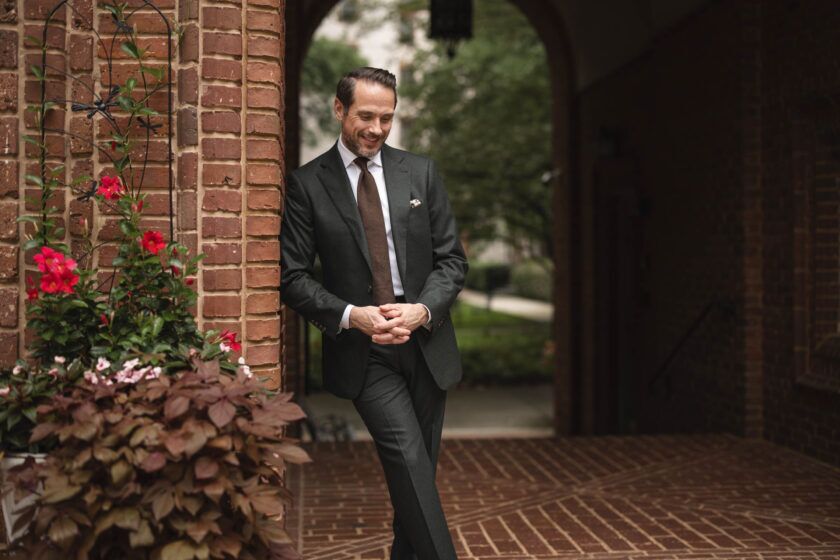 Dark green flannel suit with white shirt, brown knit tie and white pocket square, worn by a model outdoors
