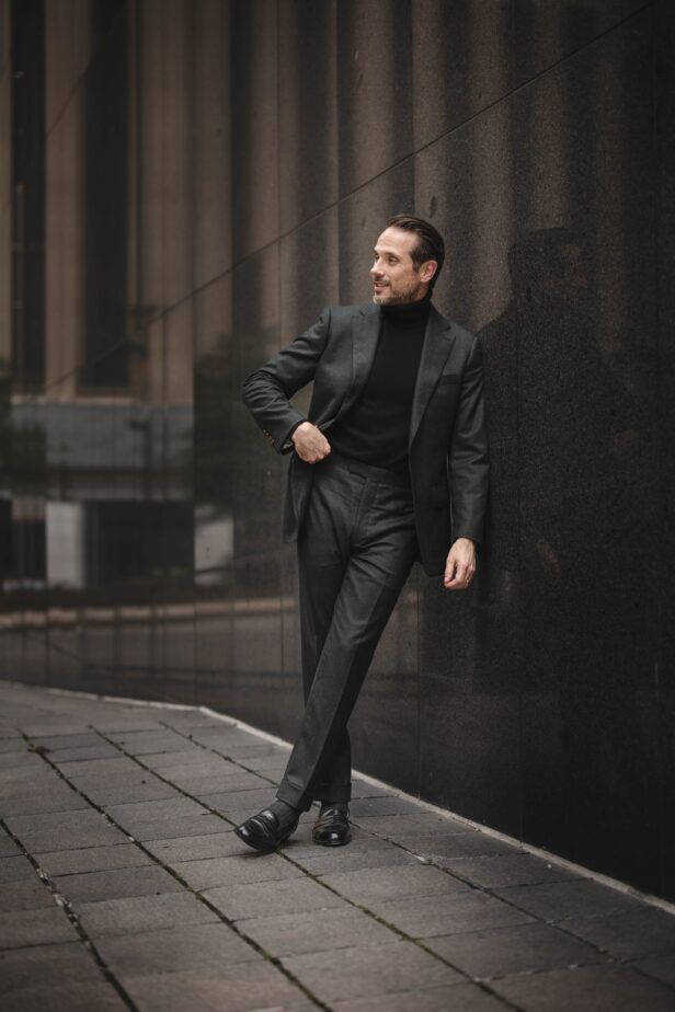 Dark green flannel suit with black turtleneck and black loafers, worn by a model in a styled street scene