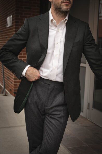 Charcoal flannel suit with green lining and white button-down shirt, worn by a model on a city sidewalk