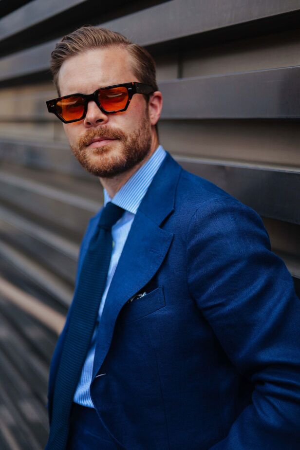 Tortoiseshell sunglasses with orange tinted lenses, worn with a blue hopsack suit and striped shirt by a model