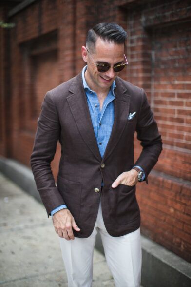 Brown linen sport coat with patch pockets, chambray shirt and cream trousers, worn by a model