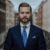Navy hopsack suit jacket with cream button-down shirt, blue patterned tie and printed pocket square, worn by a model