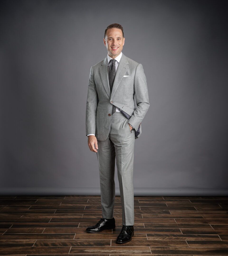 Light grey flannel suit with white shirt, grey tie, white pocket square and black oxfords, worn by a model