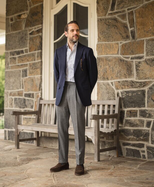 Navy flannel sport coat with striped shirt, grey flannel trousers and brown suede loafers, worn by a model